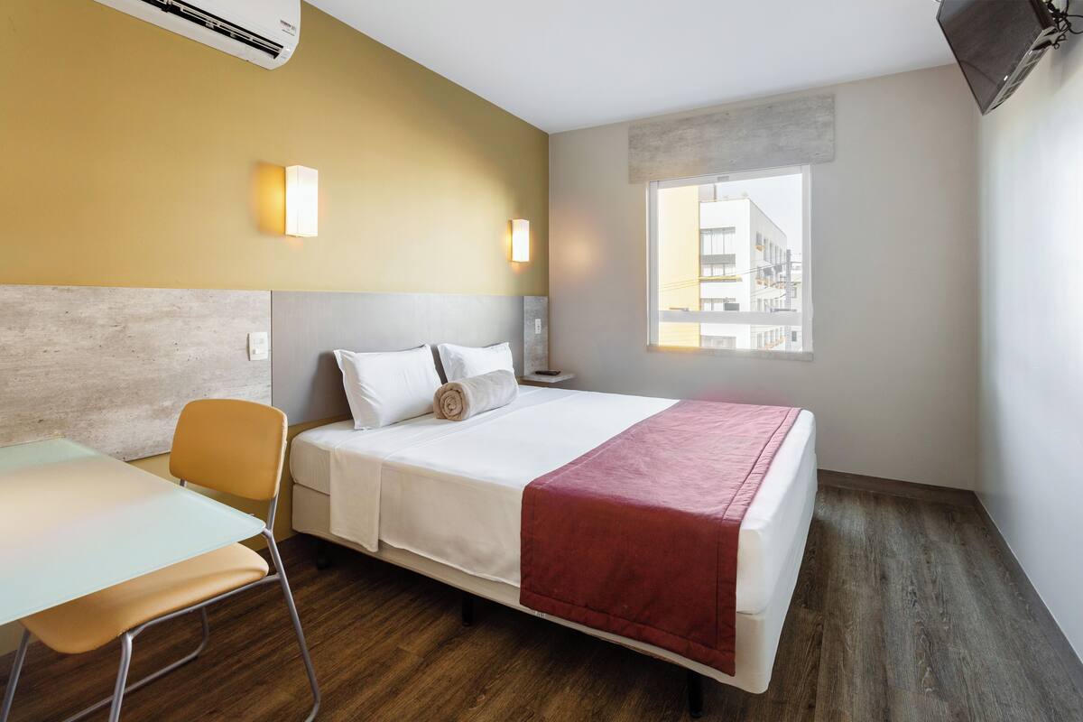 Ein modernes Hotelzimmer mit Bett, Schreibtisch und Stuhl.