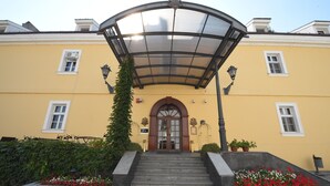 Un bâtiment à la façade jaune, doté d’une entrée couverte avec un auvent en verre et d’un escalier menant à l’entrée.