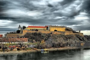Un bâtiment historique, coiffé d’un toit rouge, situé sur une colline surplombant une rivière.
