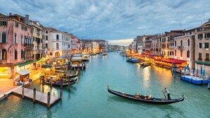 Un canal con góndolas y barcos, rodeado de edificios históricos con balcones y tiendas.
