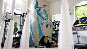 A gym with exercise equipment, a mural of a sea turtle, and a window with curtains. - Hotel Ave del Paraíso (Mercedes)