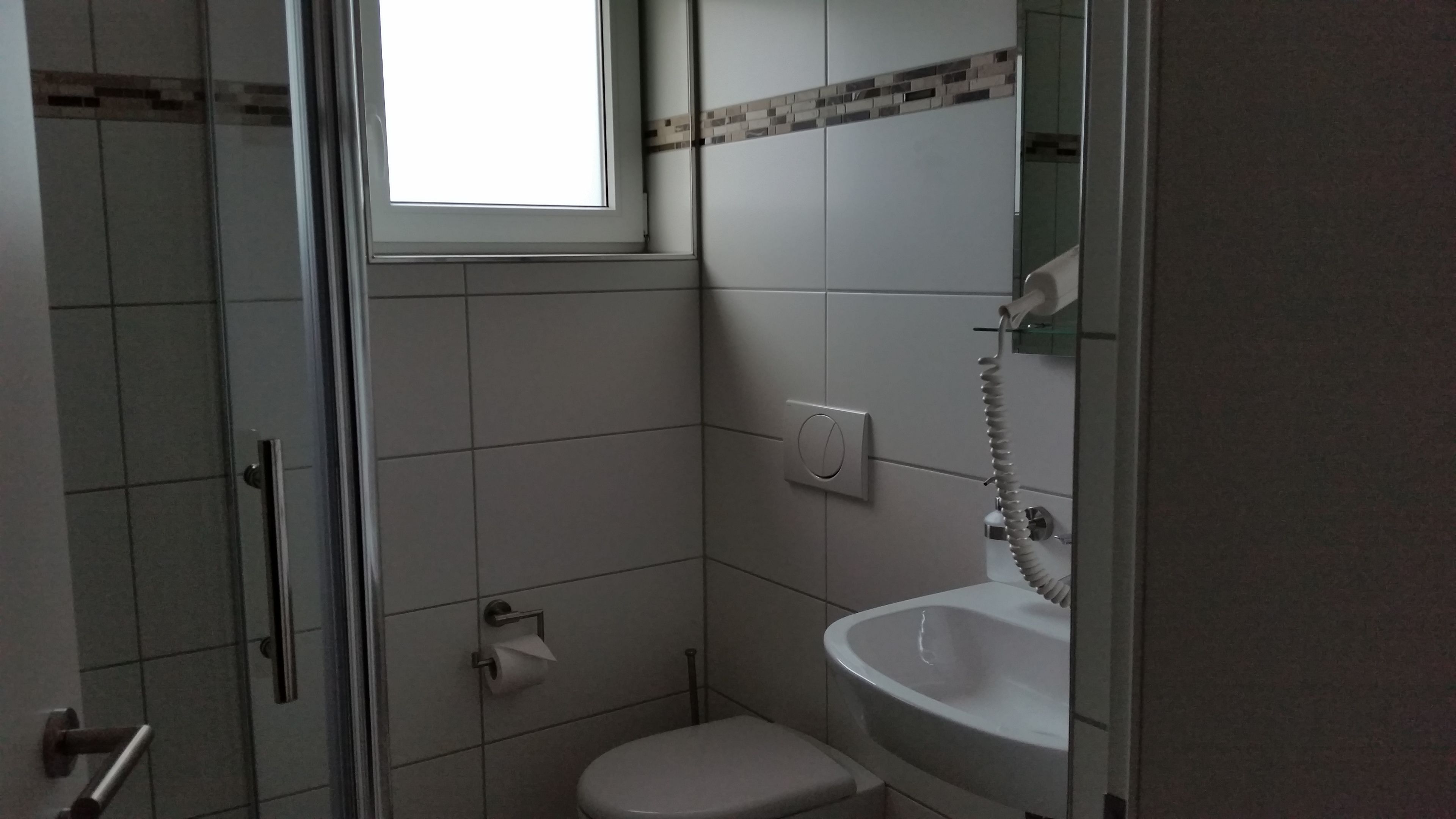 A small bathroom with a toilet, sink, and shower.