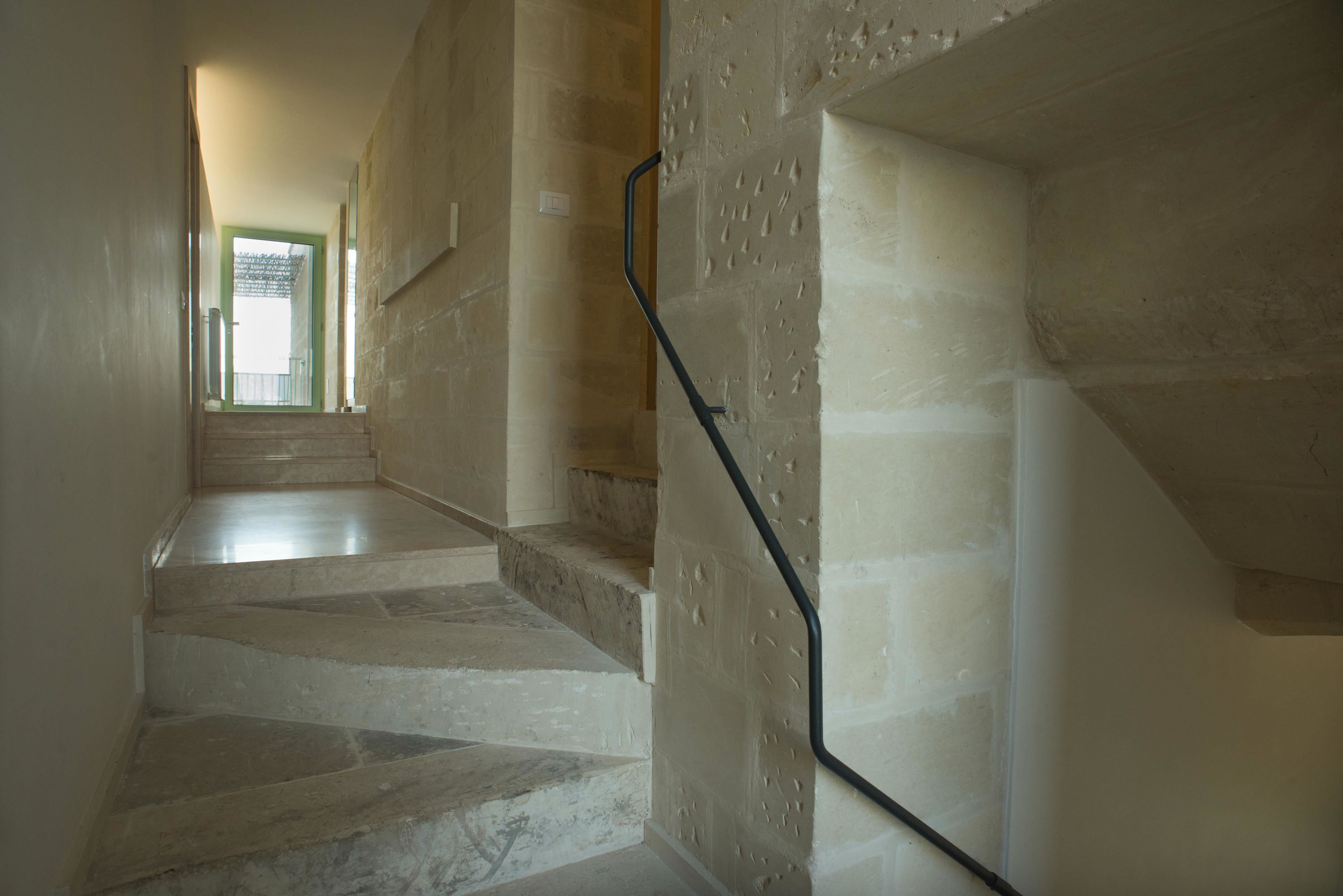 Una escalera de piedra con barandilla, que lleva a una puerta con marco verde.