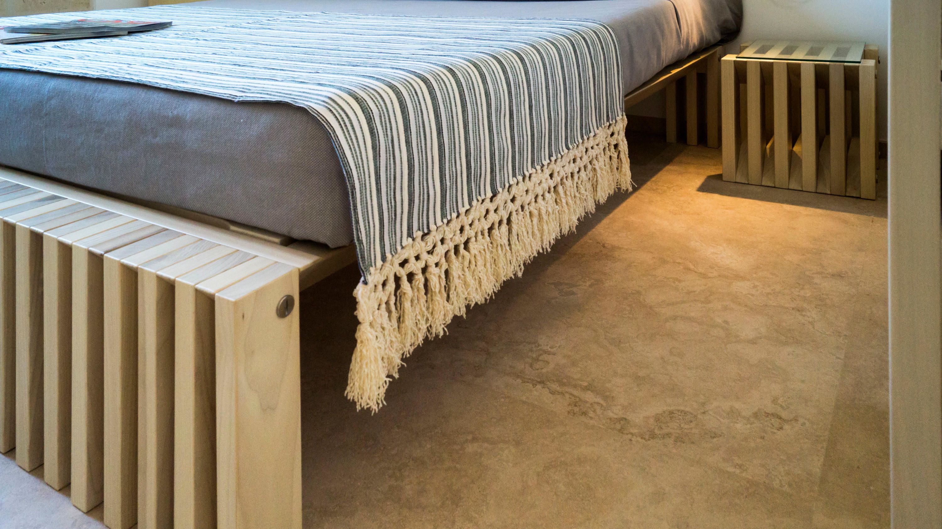 A bed with a striped blanket and a wooden headboard.