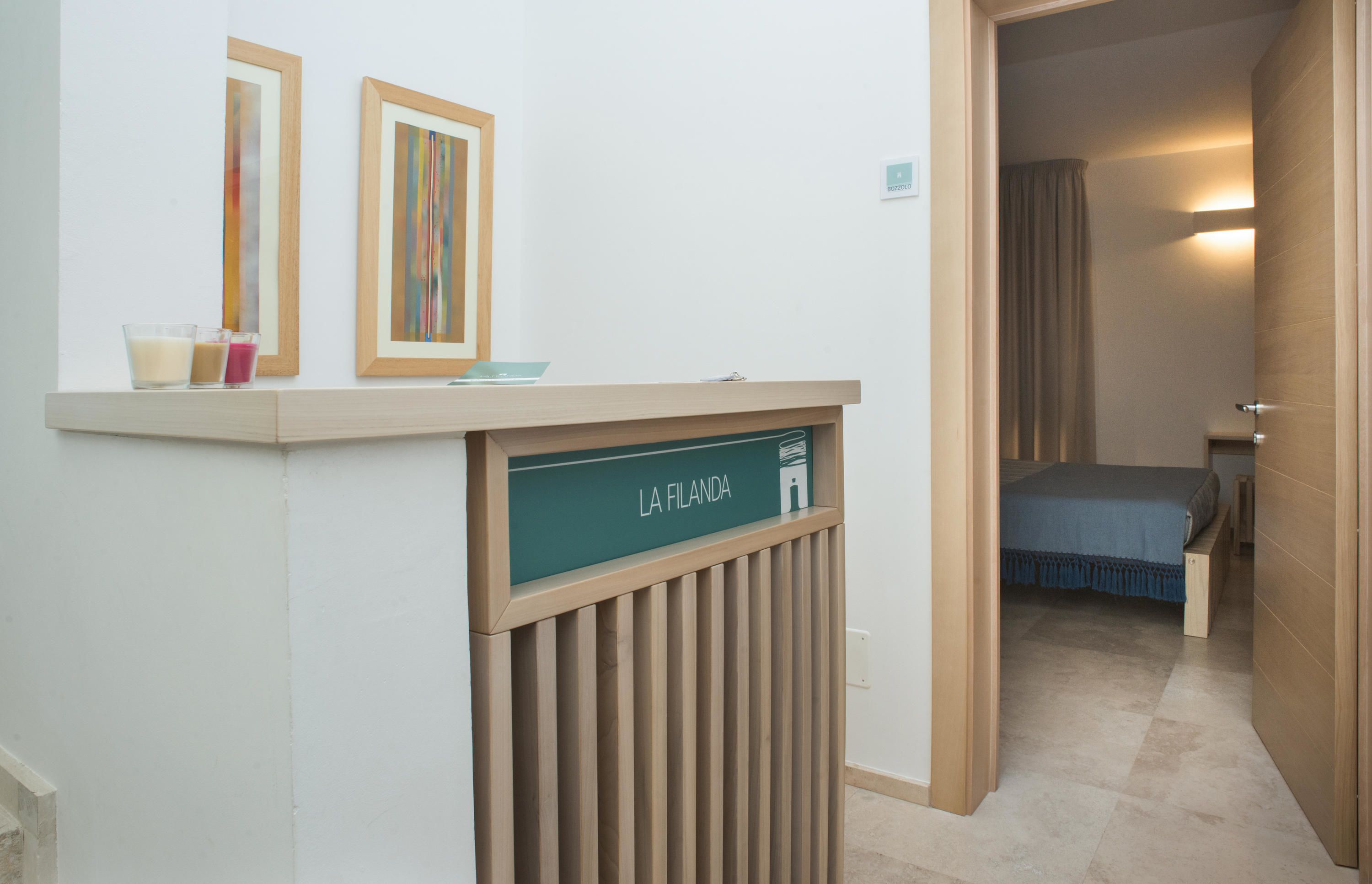 Un espace d’accueil d’hôtel avec un comptoir, des œuvres d’art encadrées et une enseigne indiquant « LA FILANDA ».