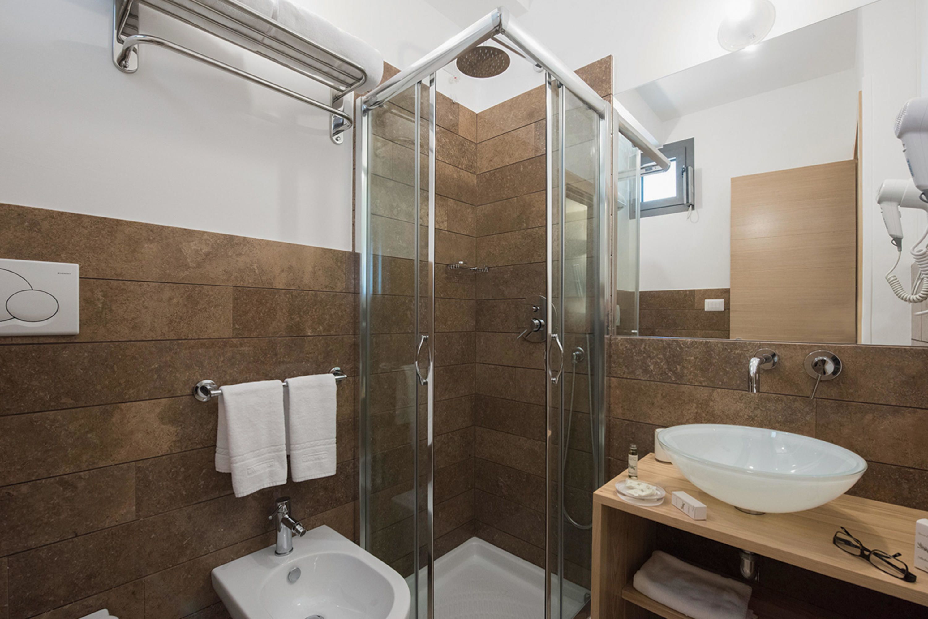 Un baño moderno con ducha acristalada, lavabo blanco y espejo.