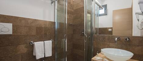 A modern bathroom with a glass-enclosed shower, a white sink, and a mirror.