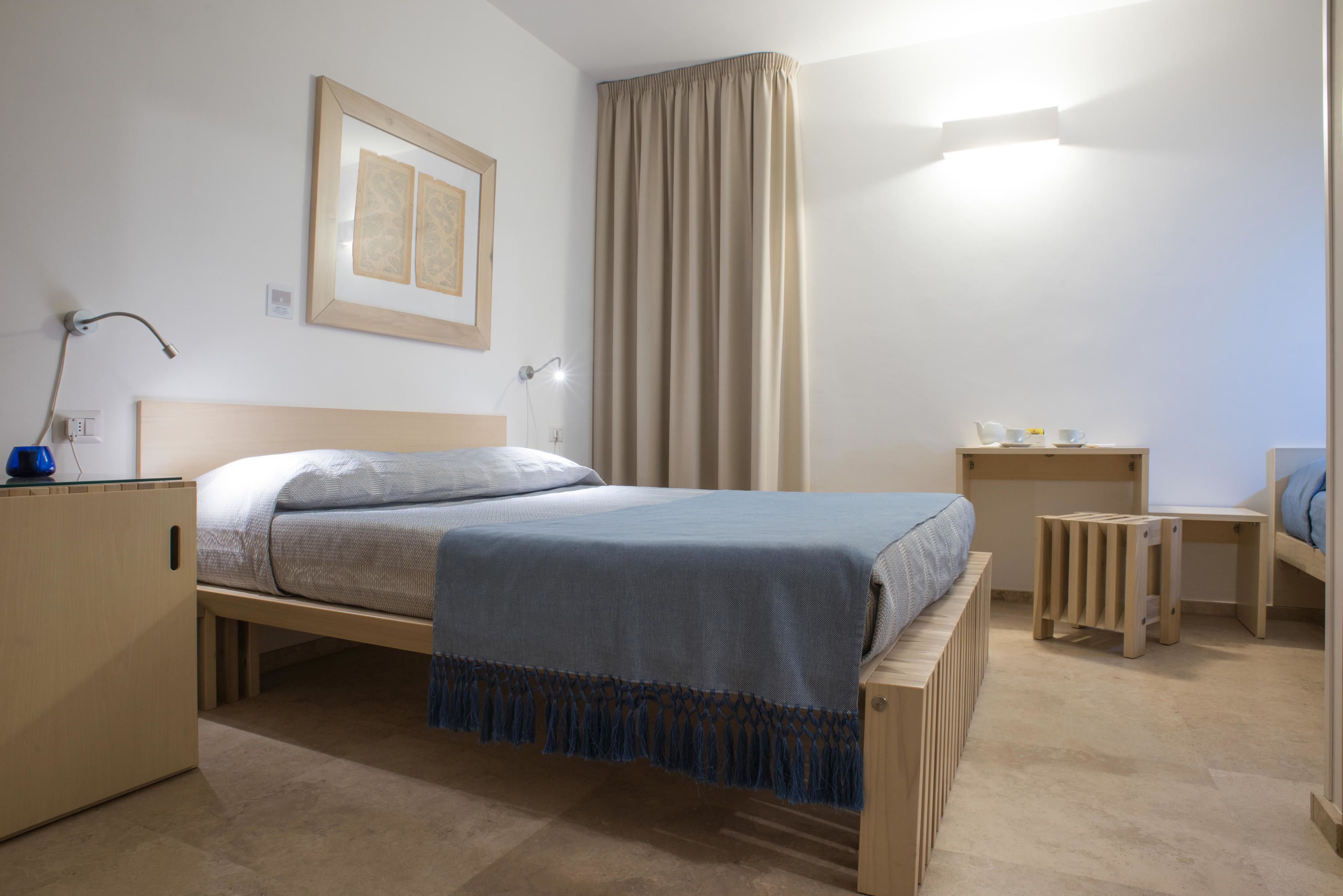 A bedroom with a bed, bedside tables, a desk, and a wardrobe.