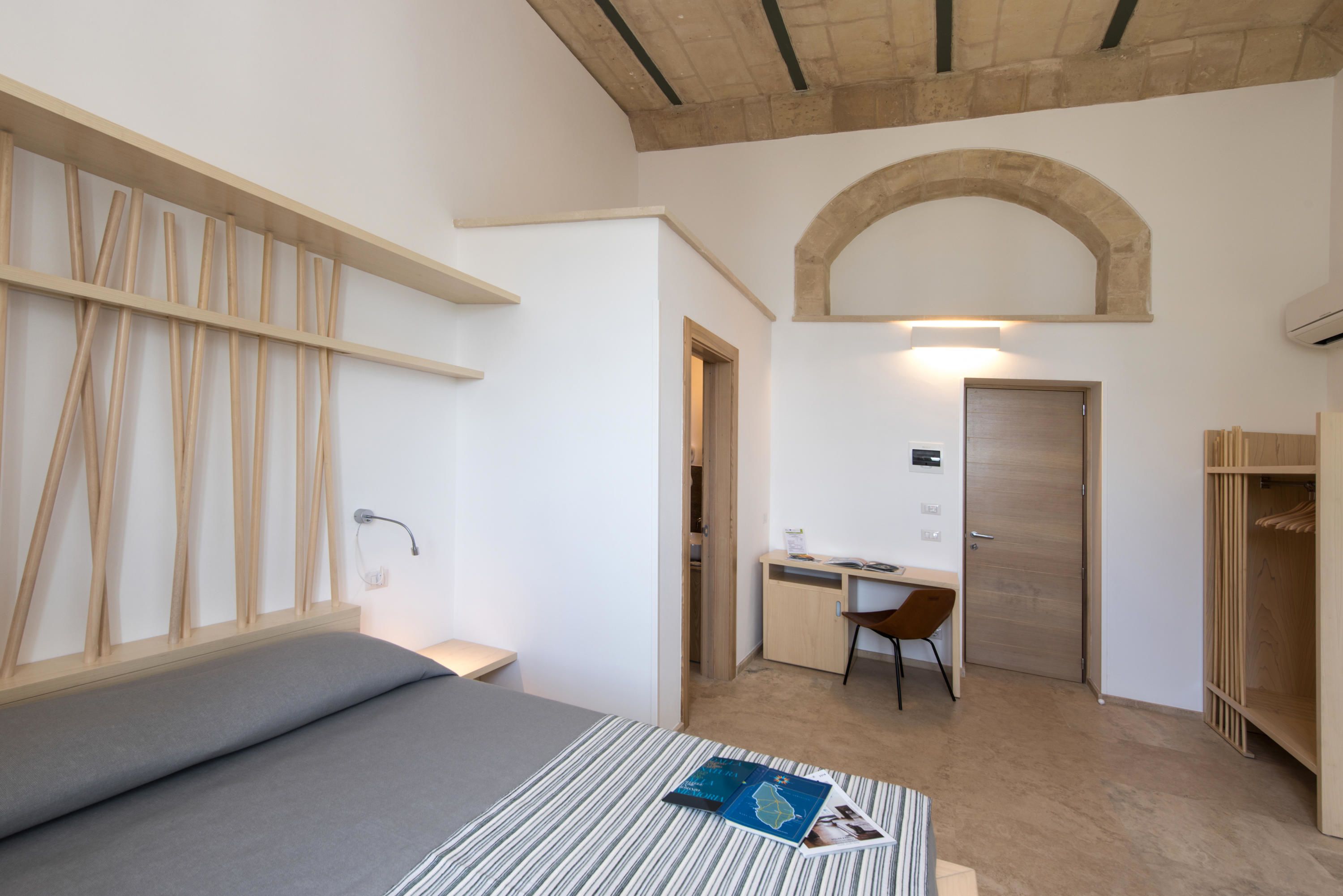 A bedroom with a bed, a desk, and a wardrobe.