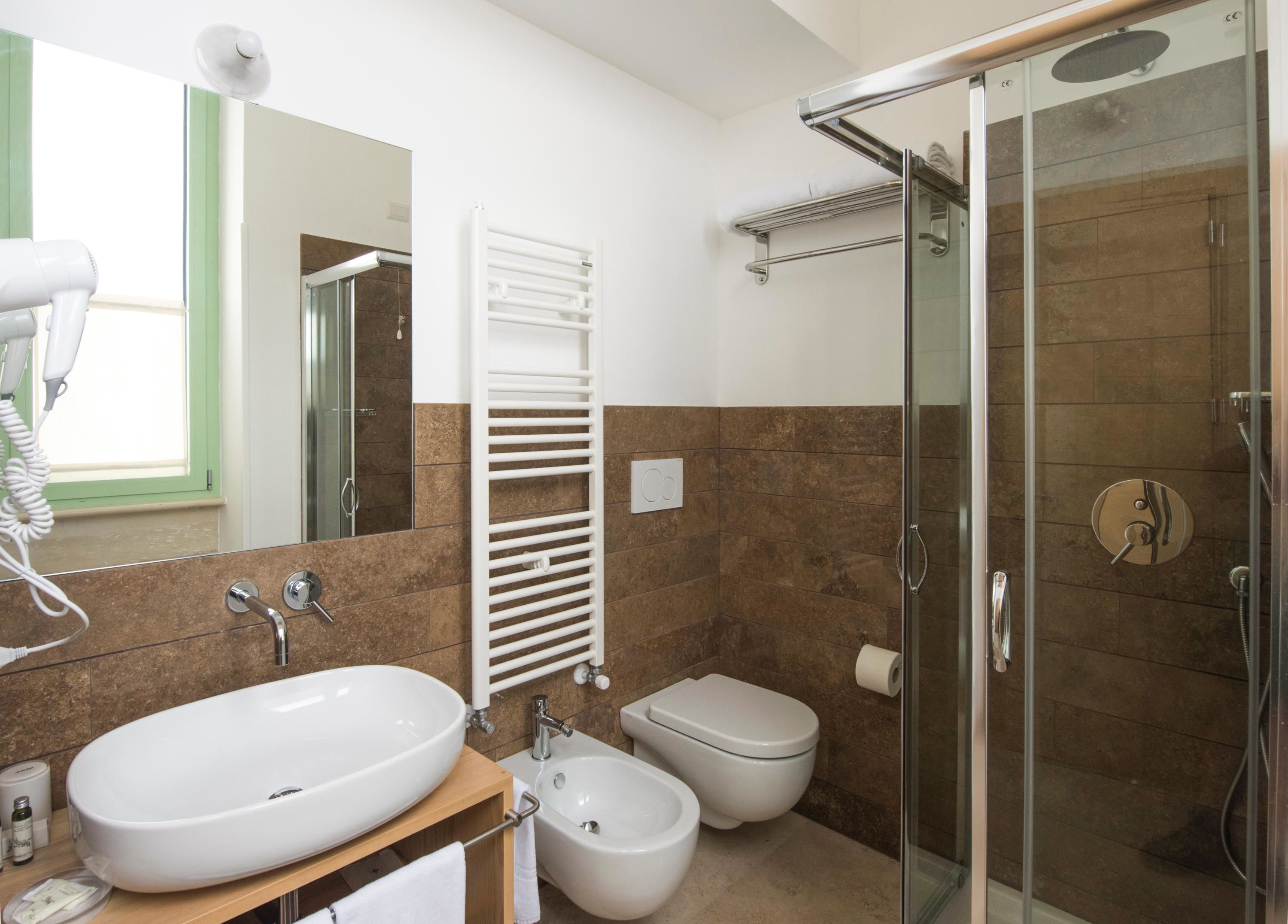 A modern bathroom with a large sink, bidet, toilet, and a glass-enclosed shower area.