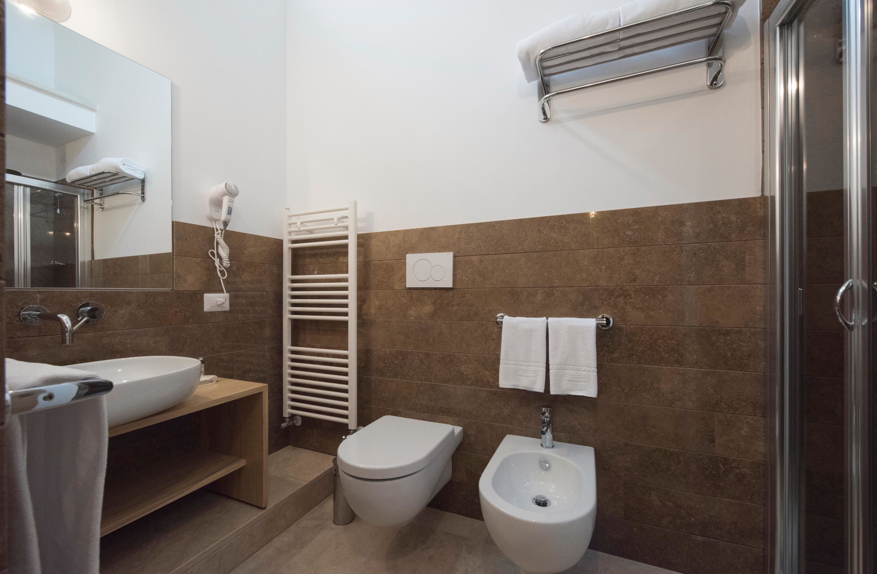A modern bathroom with a sink, toilet, bidet, and a towel rack.