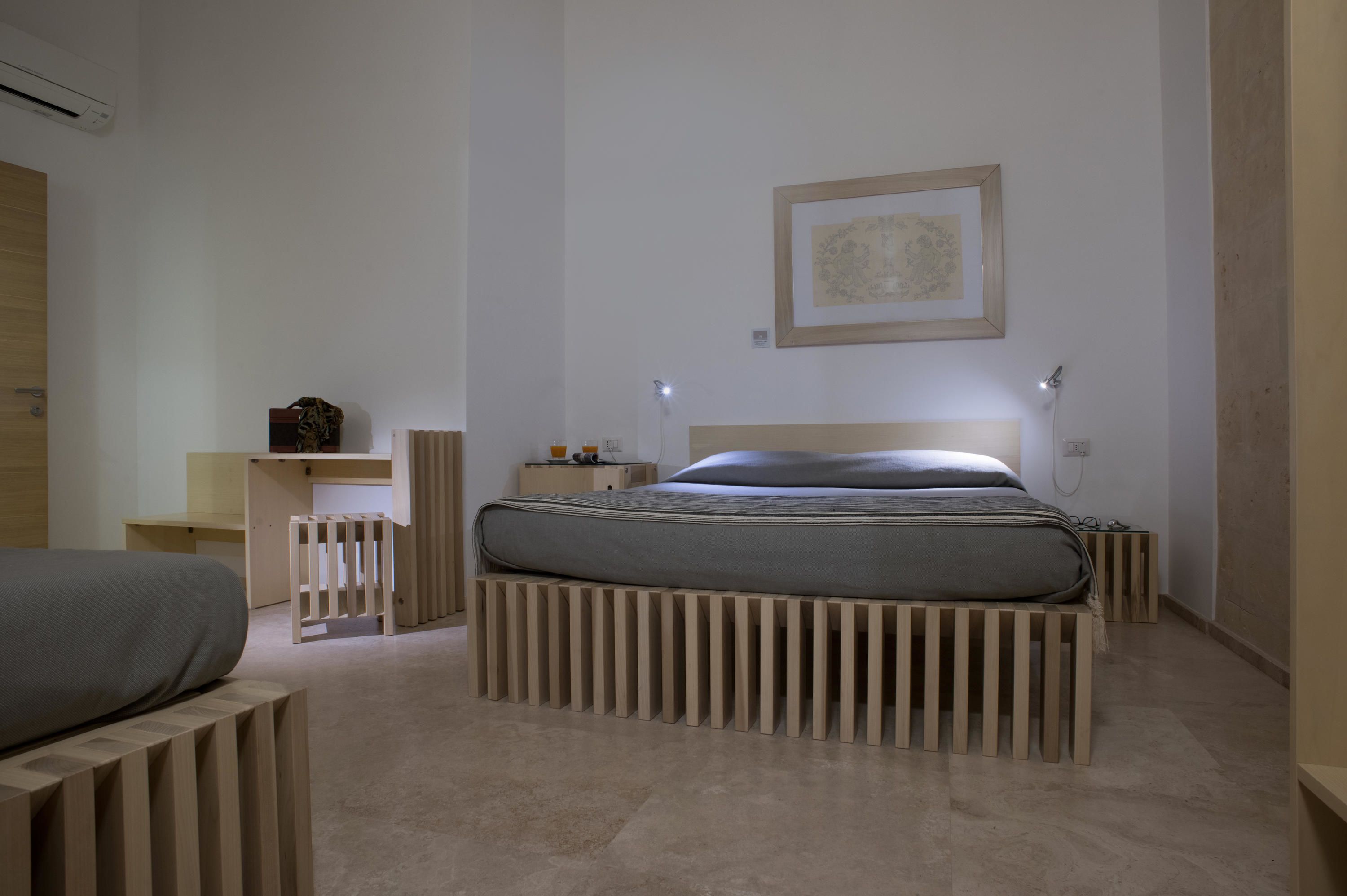 A minimalist bedroom with a bed, bedside tables, and a wall-mounted picture.