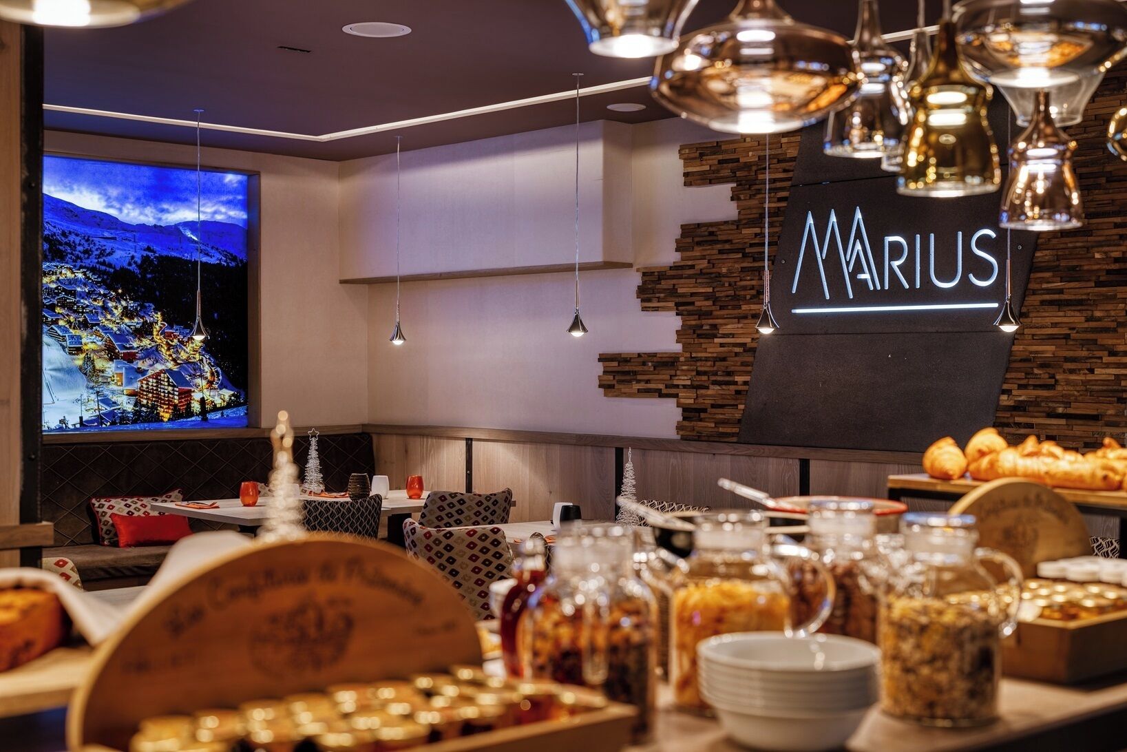 A restaurant with a modern interior, a large TV screen displaying a snowy village, and a sign reading "MARIUS".