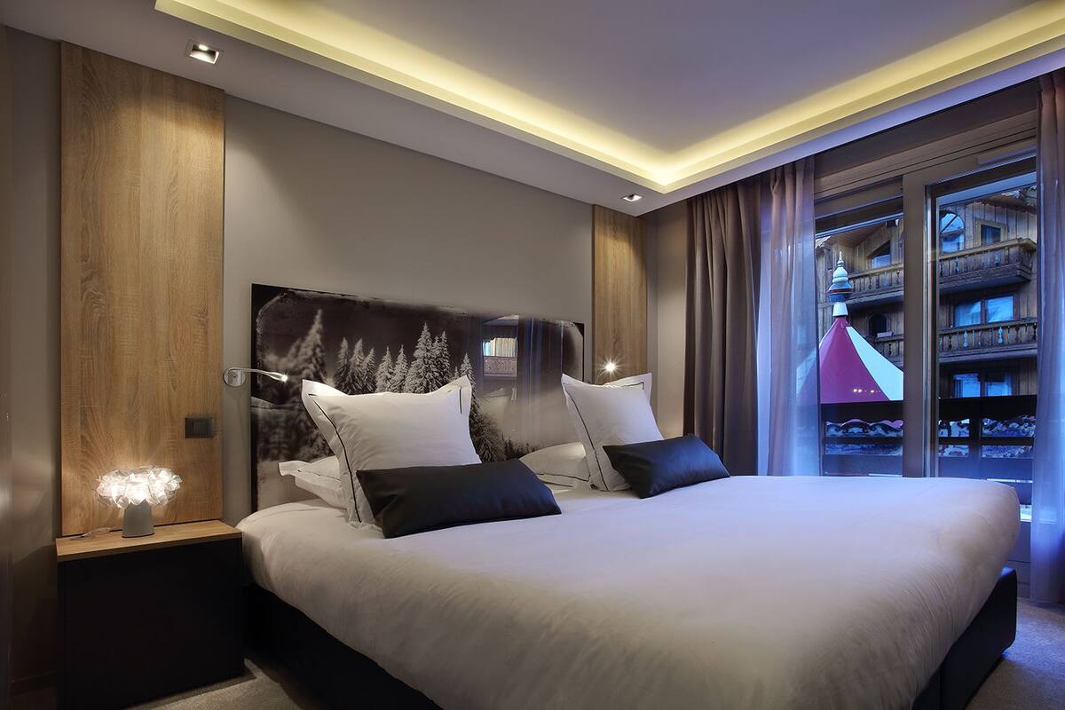 Een moderne hotelkamer met een groot bed, houten lambrisering en uitzicht op een gebouw.