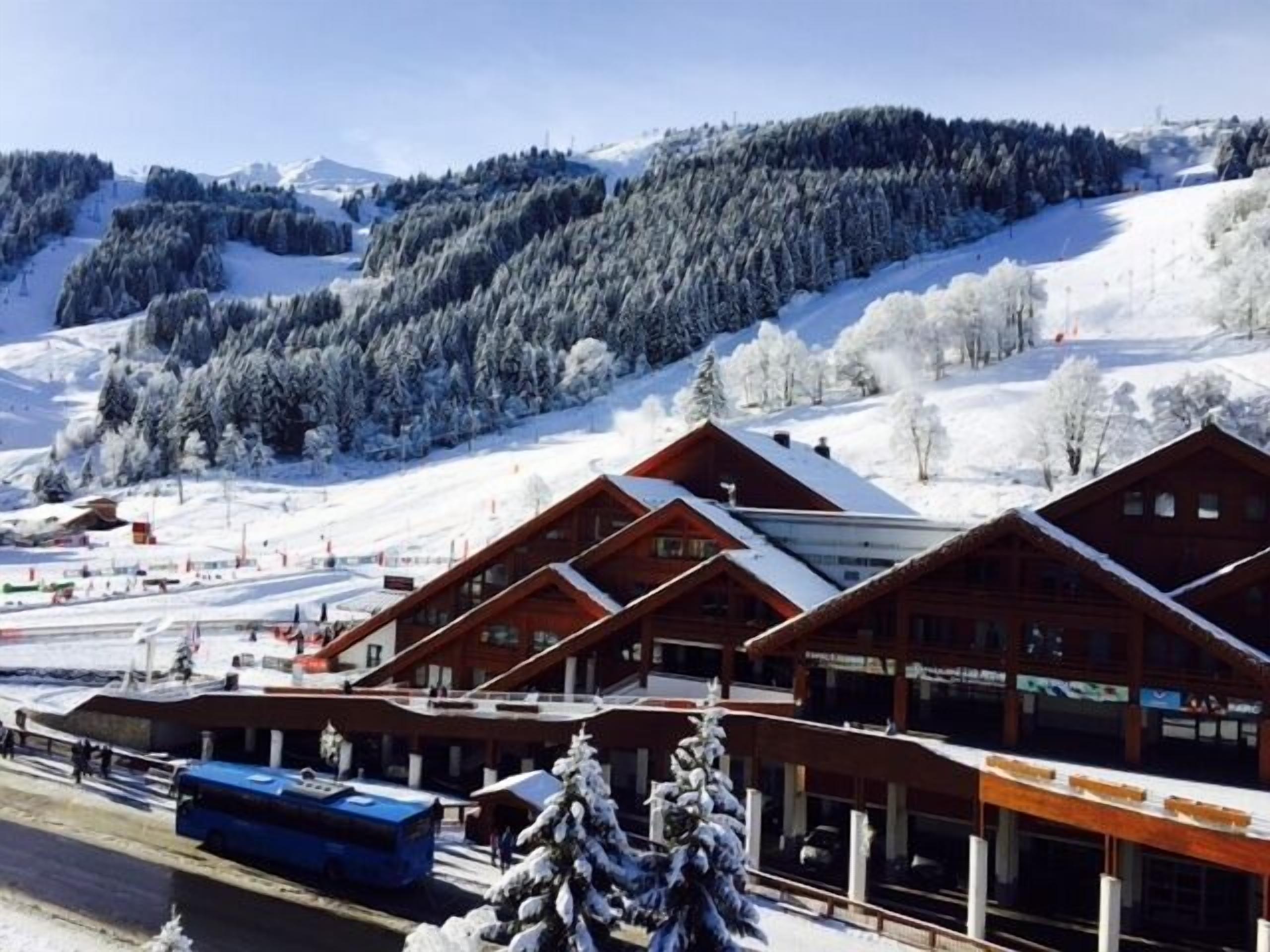 A lodge with multiple wooden cabins, a ski lift, and a snow-covered mountain backdrop.