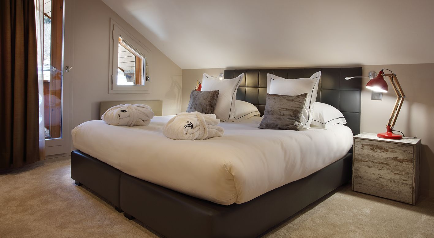 Une chambre moderne avec un grand lit, deux tables de chevet, une commode et une fenêtre avec des rideaux.