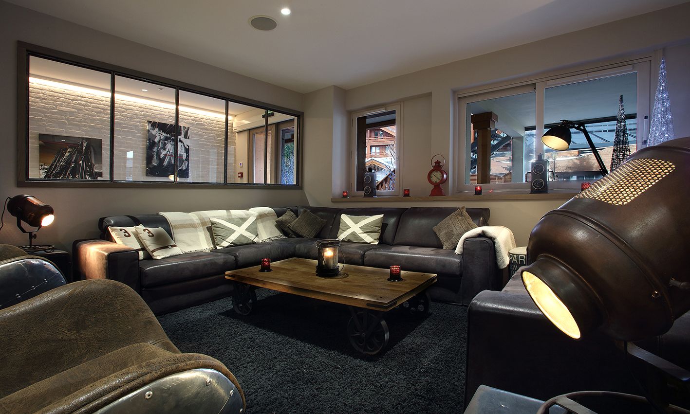 A modern living room with a sectional sofa, a coffee table, and a large window with a view of a building.
