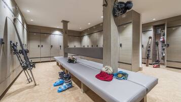A ski lodge with lockers, benches, skis, and ski equipment.