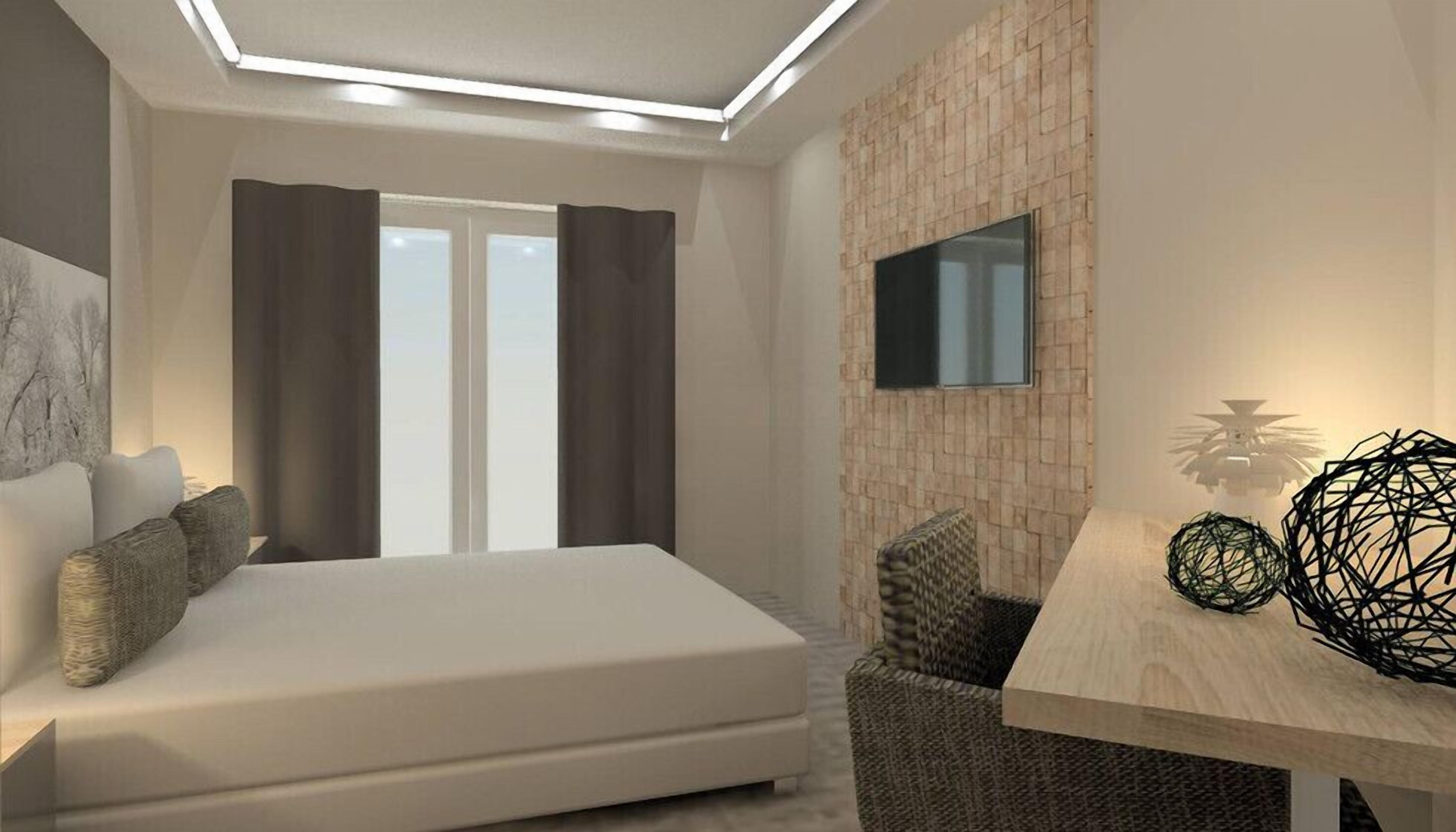 A modern hotel room with a bed, a desk, and a TV mounted on the wall.