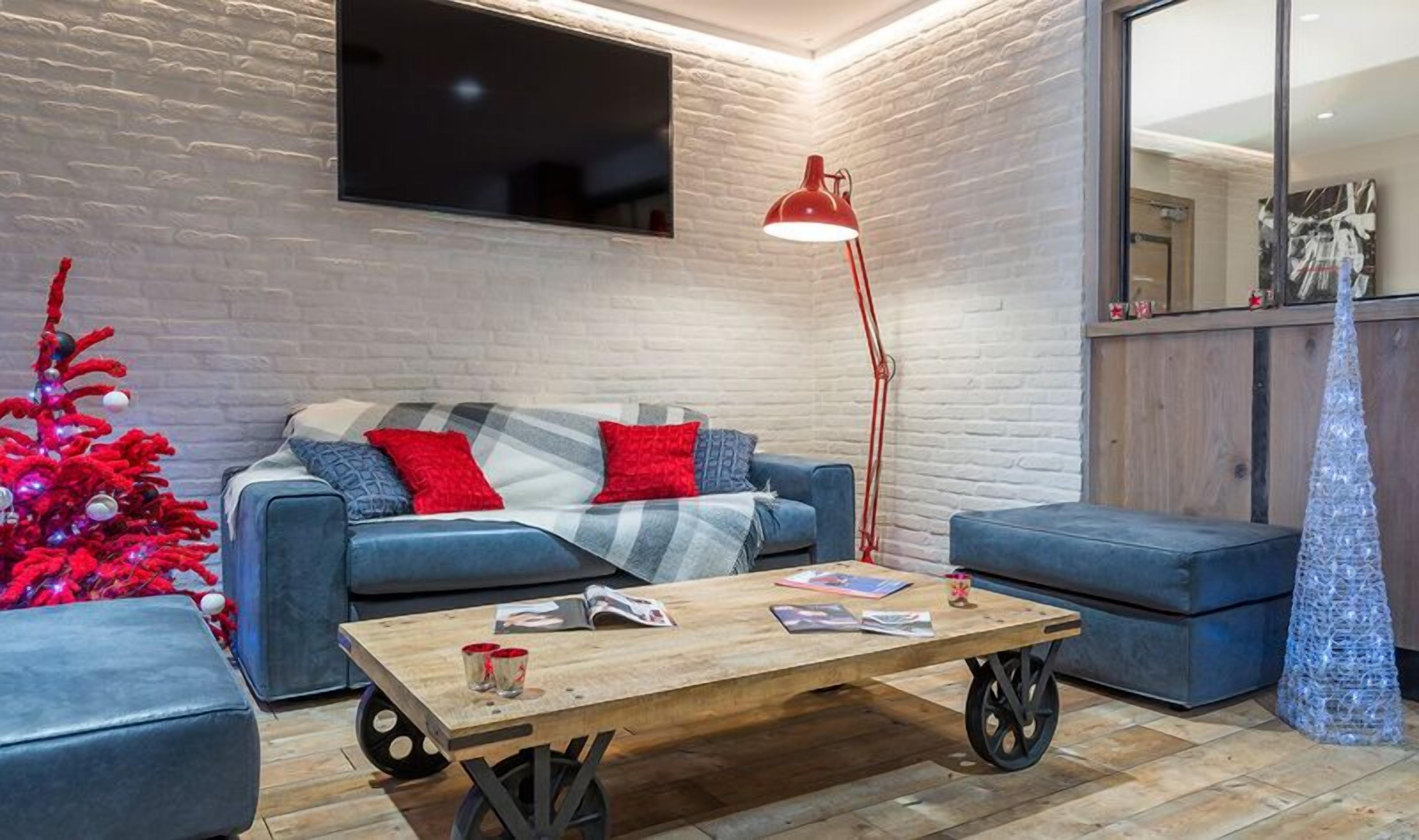 A modern living room with a blue sofa, a wooden coffee table, and a red floor lamp.
