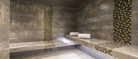 Un baño moderno con una bañera grande, un banco y una pared de azulejos con diseño de cuadros.