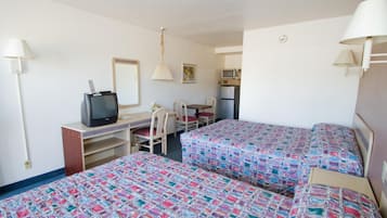 Une chambre d’hôtel avec deux lits, un bureau avec une télévision, une chaise, une table et un four à micro-ondes.