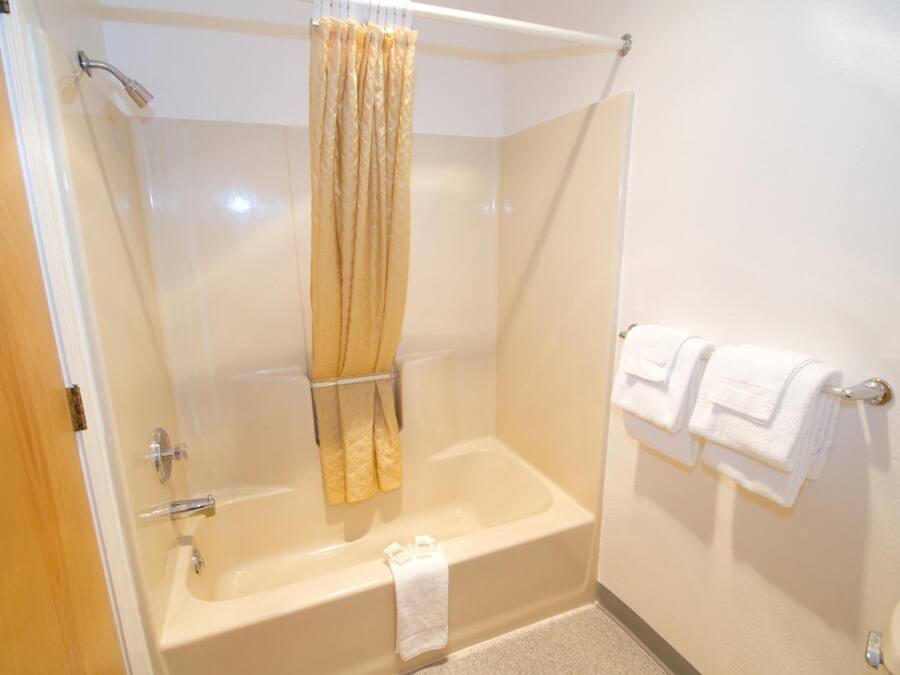 A bathroom with a bathtub, a shower curtain, and two white towels on a rack.