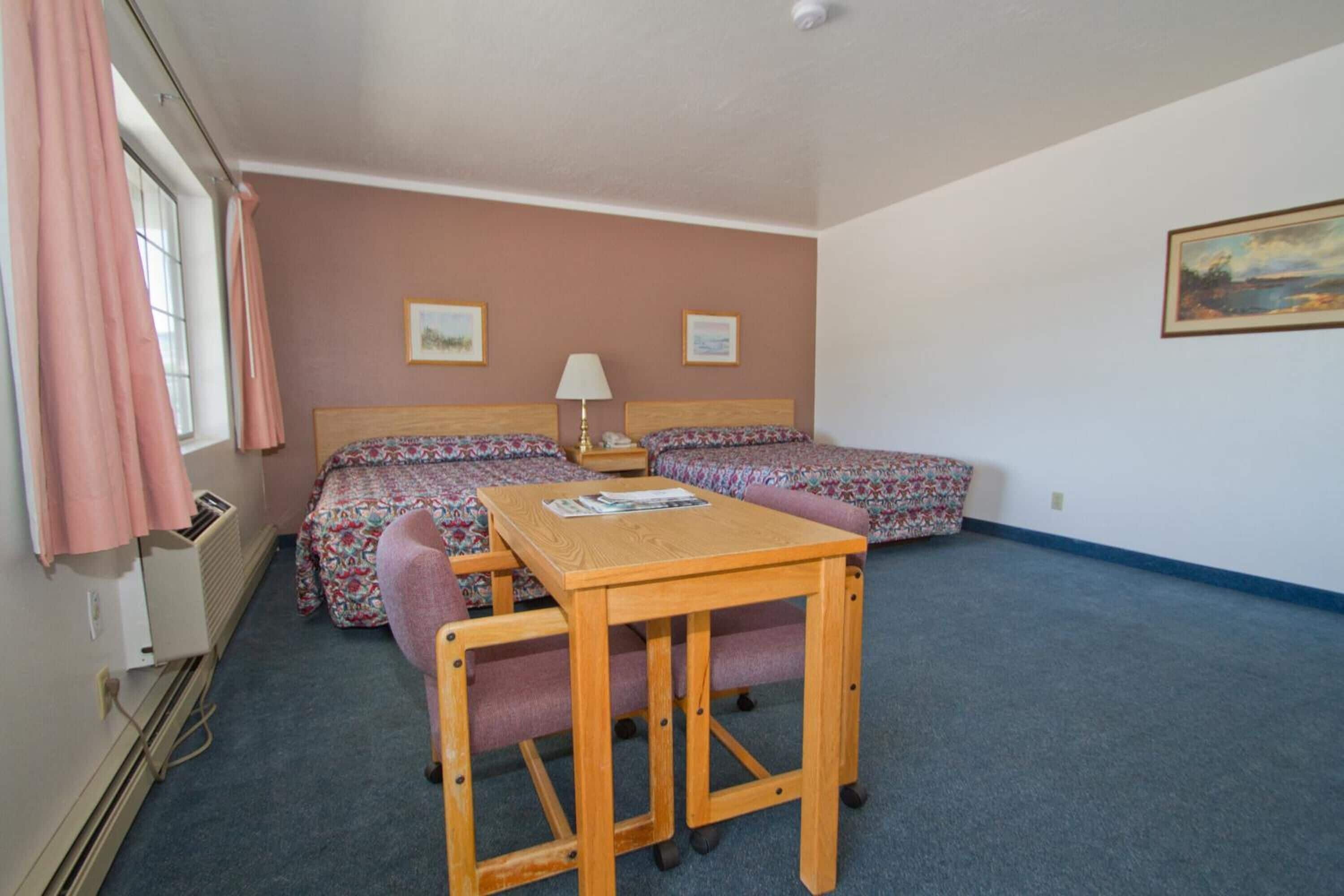 Ein Zimmer mit zwei Betten, einem Tisch und Stühlen.