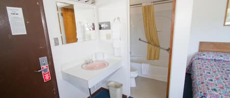 Een hotelbadkamer met een wastafel, spiegel en douche.