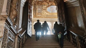 A grand staircase with ornate carvings and a large archway leading to a bright interior. - Ca' Messner 5 Leoni (Venice)