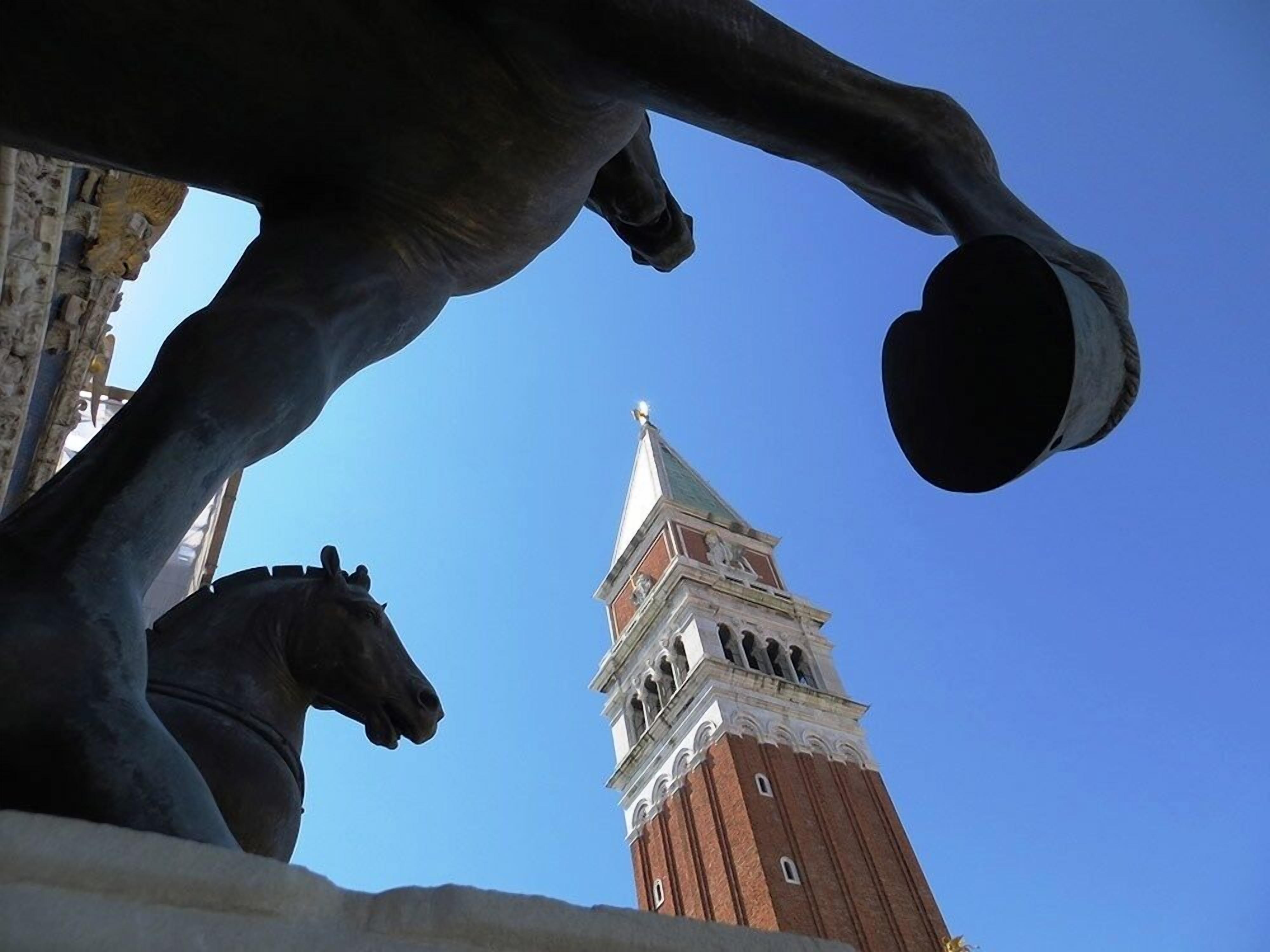 A statue of a horse with a rider, and a tower with a pointed roof in the background.