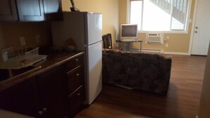 A kitchen with a refrigerator, a dining table with chairs, and a window with blinds. - Sleep Right Inn (Enderby)