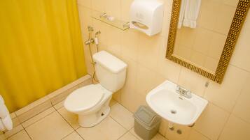 A bathroom with a toilet, sink, and a glass shelf with toiletries.