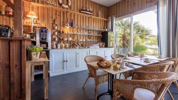A wooden-paneled kitchen with a dining area, featuring a large window, wicker furniture, and various kitchen appliances.