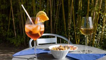 Een tafel met een drankje, een schaal nootjes en een wijnglas.