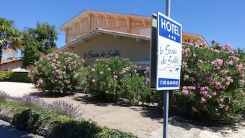 A hotel named "le Grain de Sable" with a signboard displaying the name and contact number.