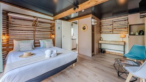 A modern bedroom with a large bed, wooden slats on the walls, a desk, and a chair.