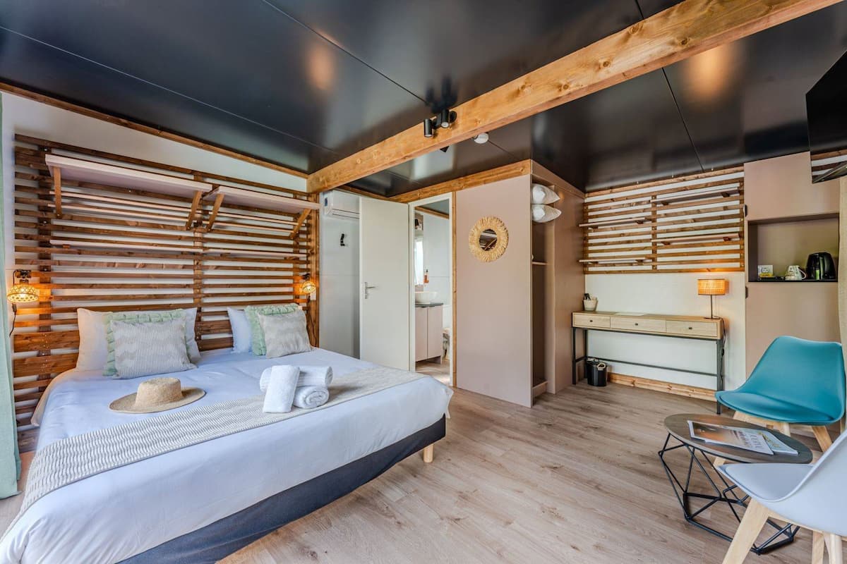 A modern bedroom with a large bed, wooden slats on the walls, a desk, and a chair.