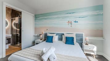 Habitación de hotel con una cama grande, cabina de ducha de vidrio y un mural de playa en la pared.