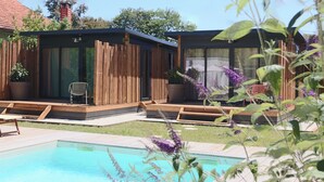 A modern outdoor pool area with wooden structures and a clear blue pool.