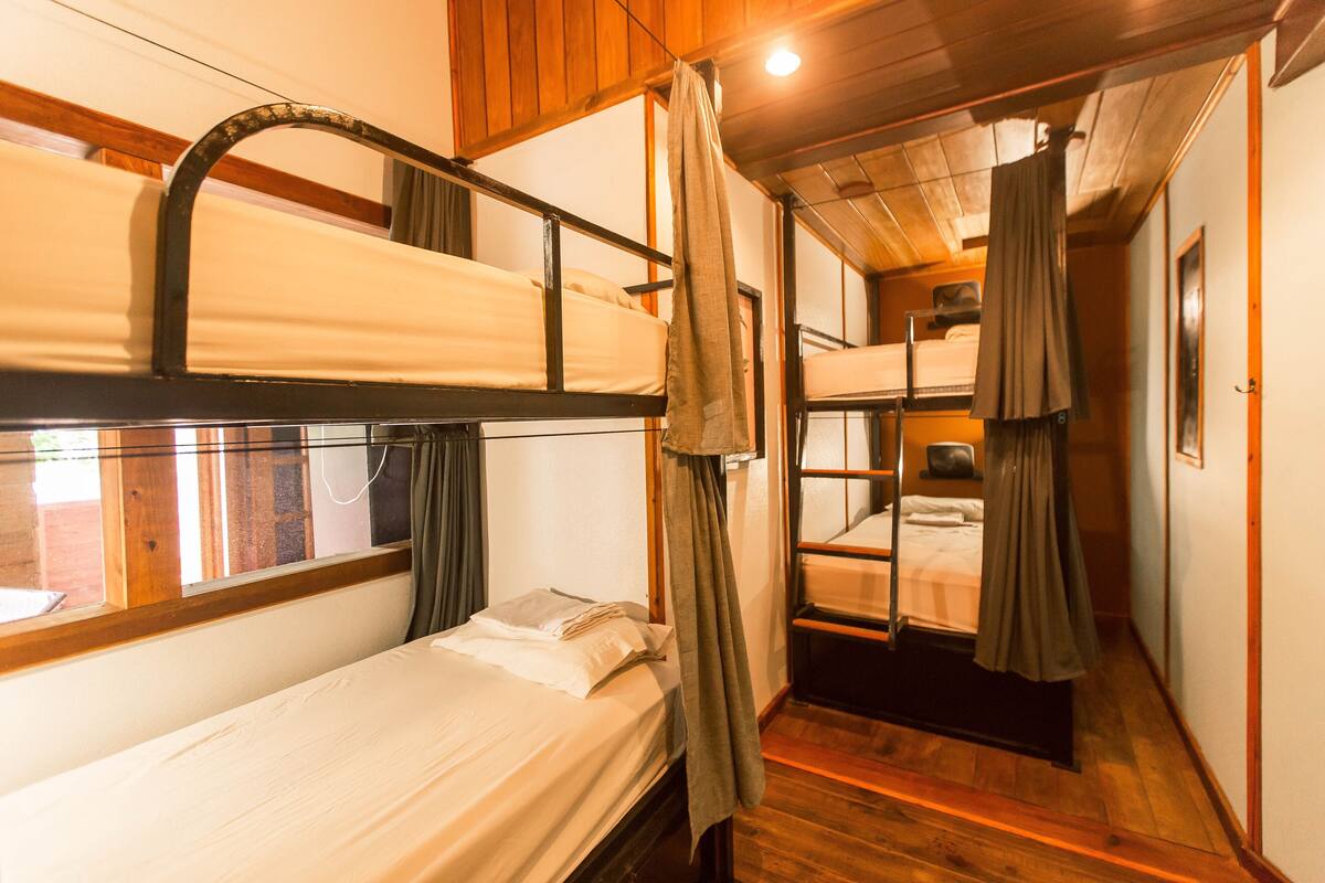 A compact, multi-bed cabin with bunk beds, wooden walls, and a small window.