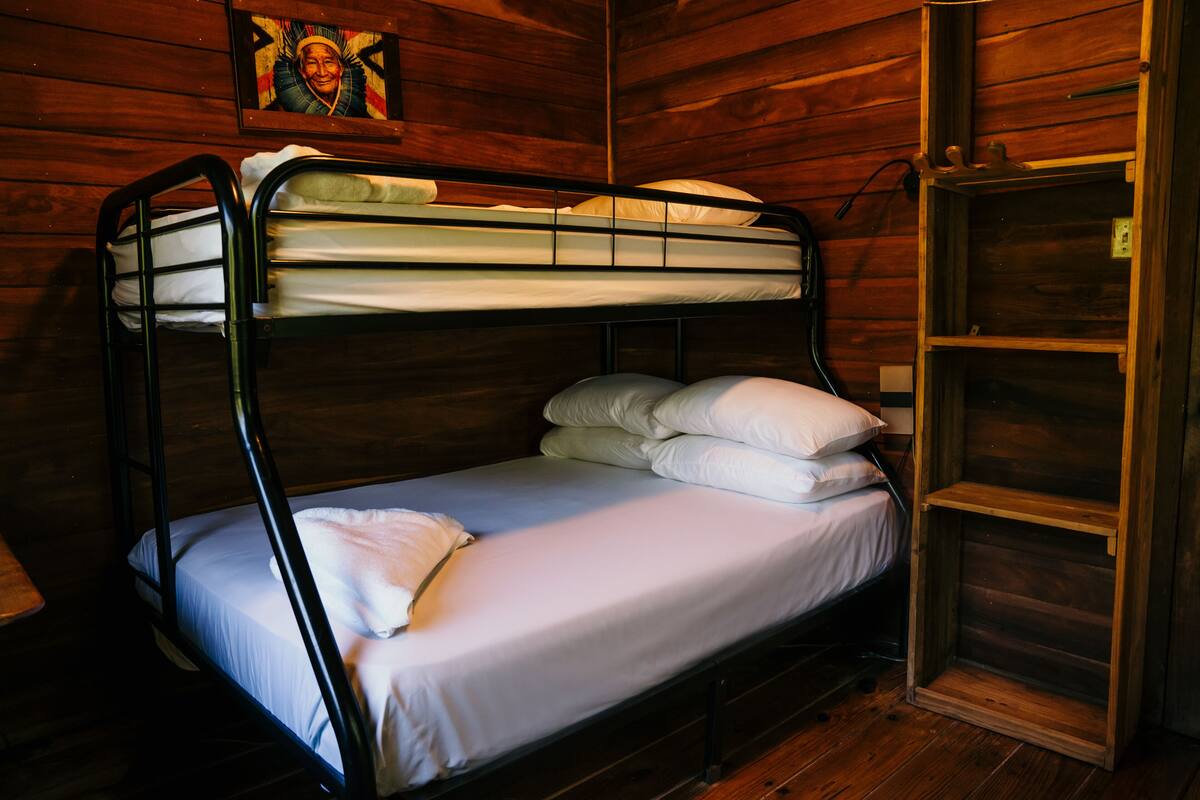 A bunk bed with white bedding in a wooden room.