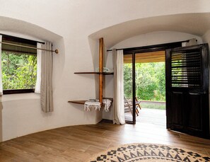 A room with a wooden floor, a large window with curtains, a wooden beam, and a door leading outside. - Bambuda Lodge - Hostel (Bastimentos)