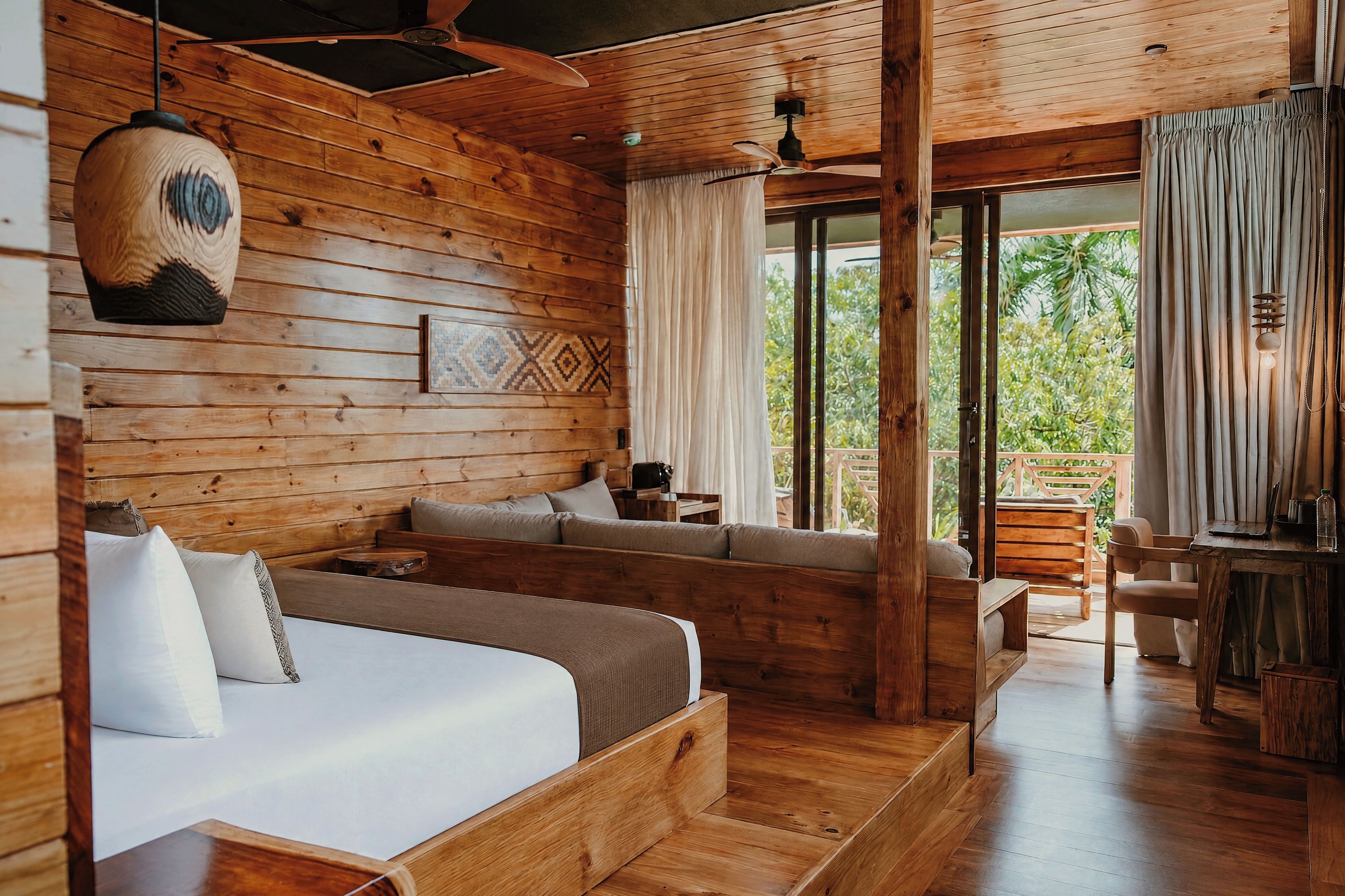 A wooden cabin interior with a bed, seating area, and a dining space.