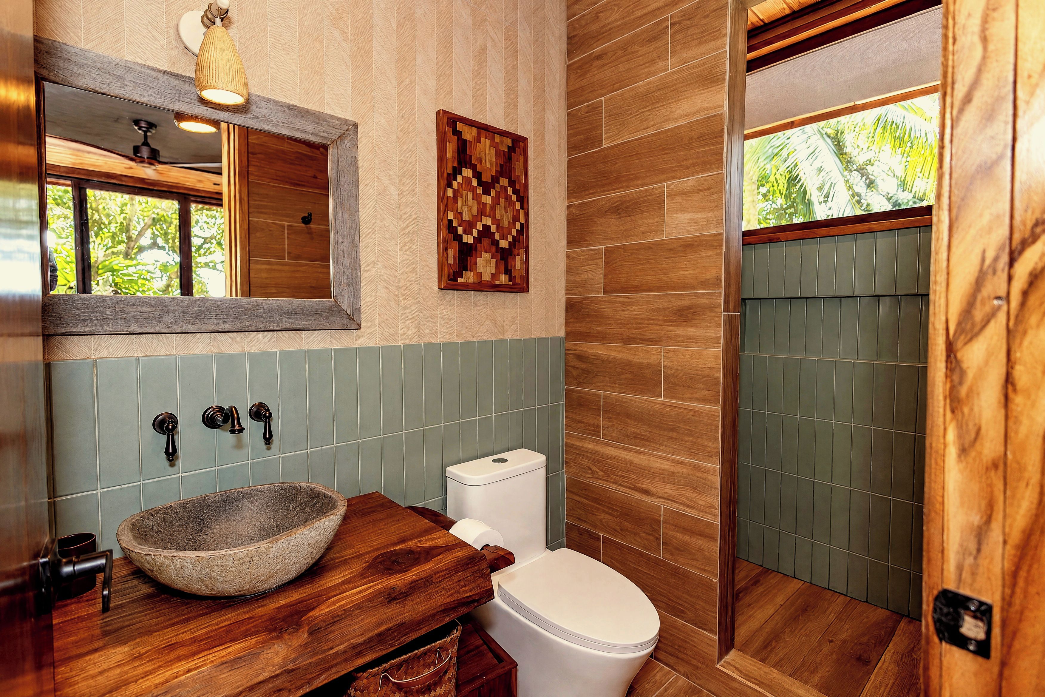 Ein Badezimmer mit einem Steinkran, einem Holzschranken, einer Toilette und einer Duschkabine.