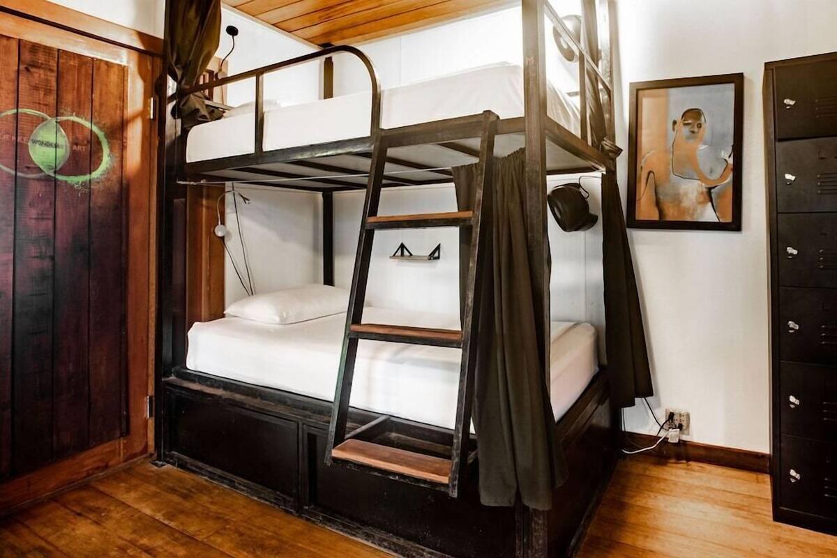 A bunk bed room with a ladder, wooden floor, and a wall with a circular design.