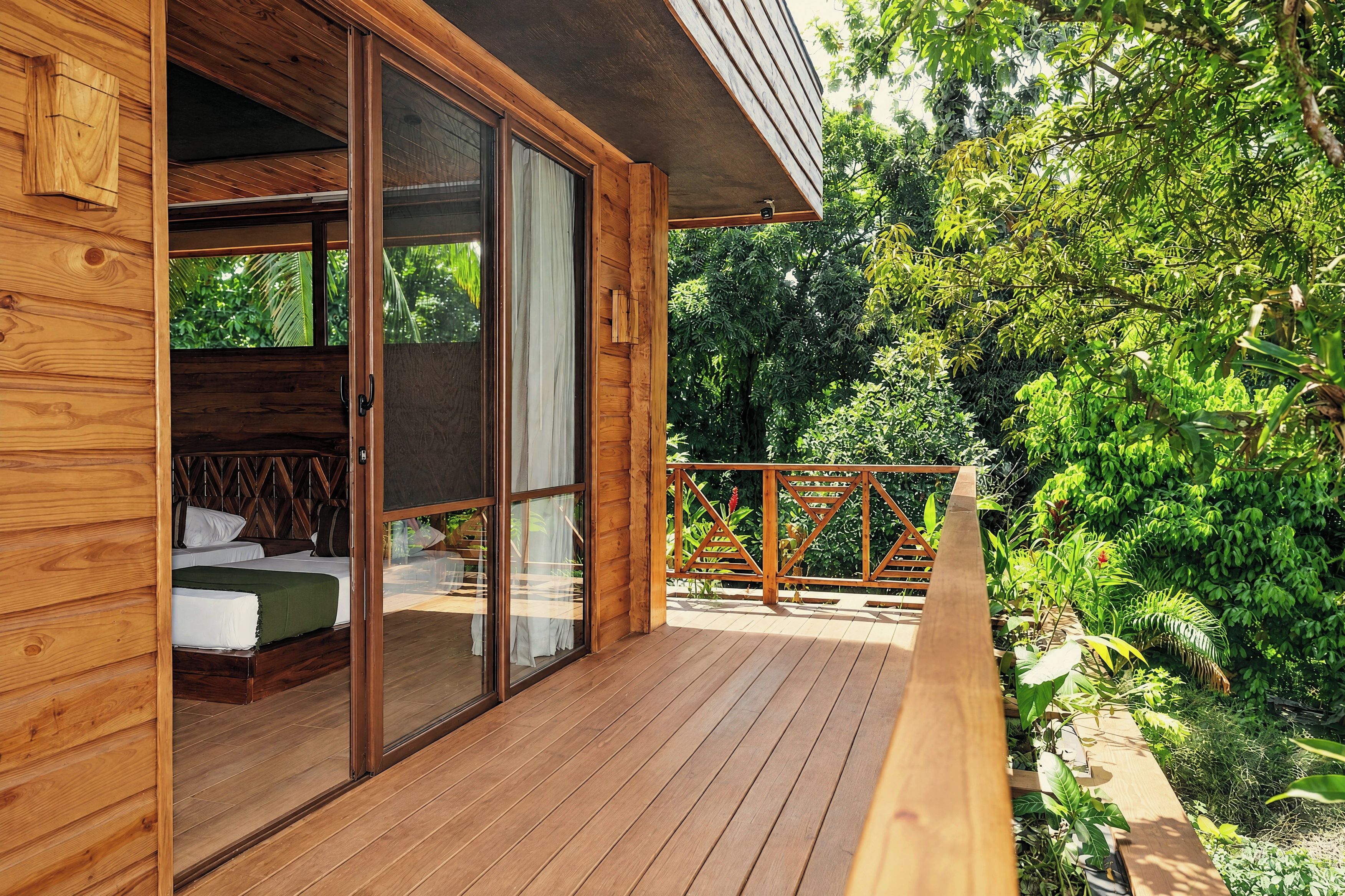 A wooden cabin with a sliding glass door leading to a bedroom with a bed and a window.