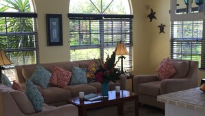 A living room with two sofas, a coffee table, and a small table with a vase of flowers.