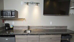 A kitchen with a microwave, sink, and a flat-screen TV mounted on the wall. - Nature's Inn Kenora (Kenora)