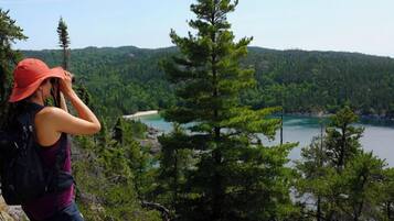 Une personne prend une photo d’un lac entouré d’une forêt dense et de collines.